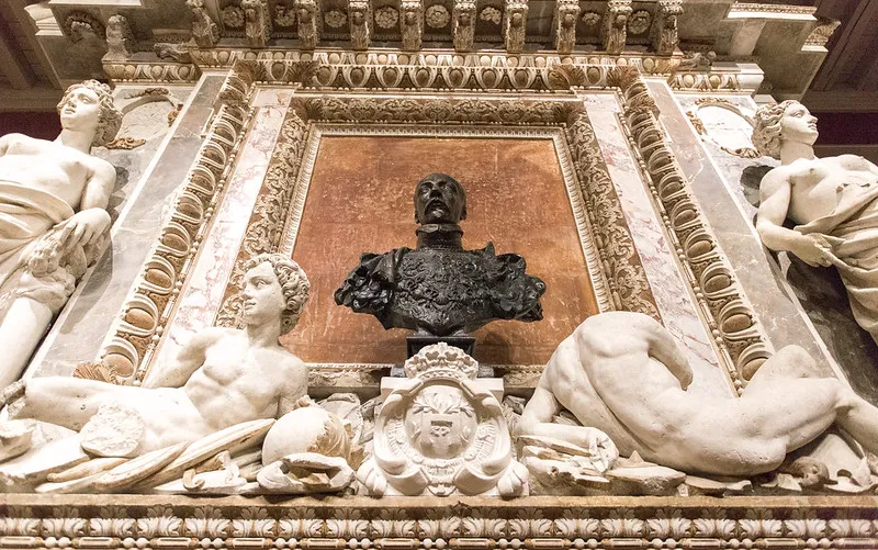 Interior architectural decoration at Château de Cadillac featuring a bronze bust on terracotta background, surrounded by white marble sculptures and gilded classical ornaments.