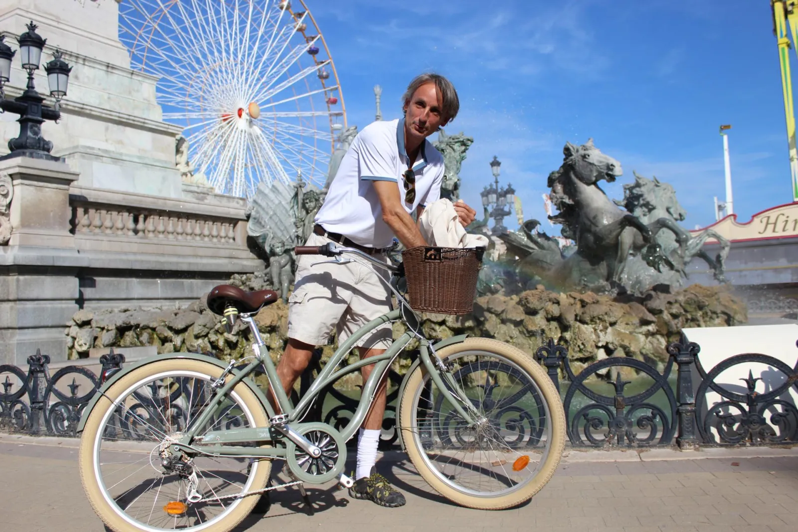 Man on a vintage bicycle in front of the Ferris wheel and horse statues at Place de la Bourse in Bordeaux