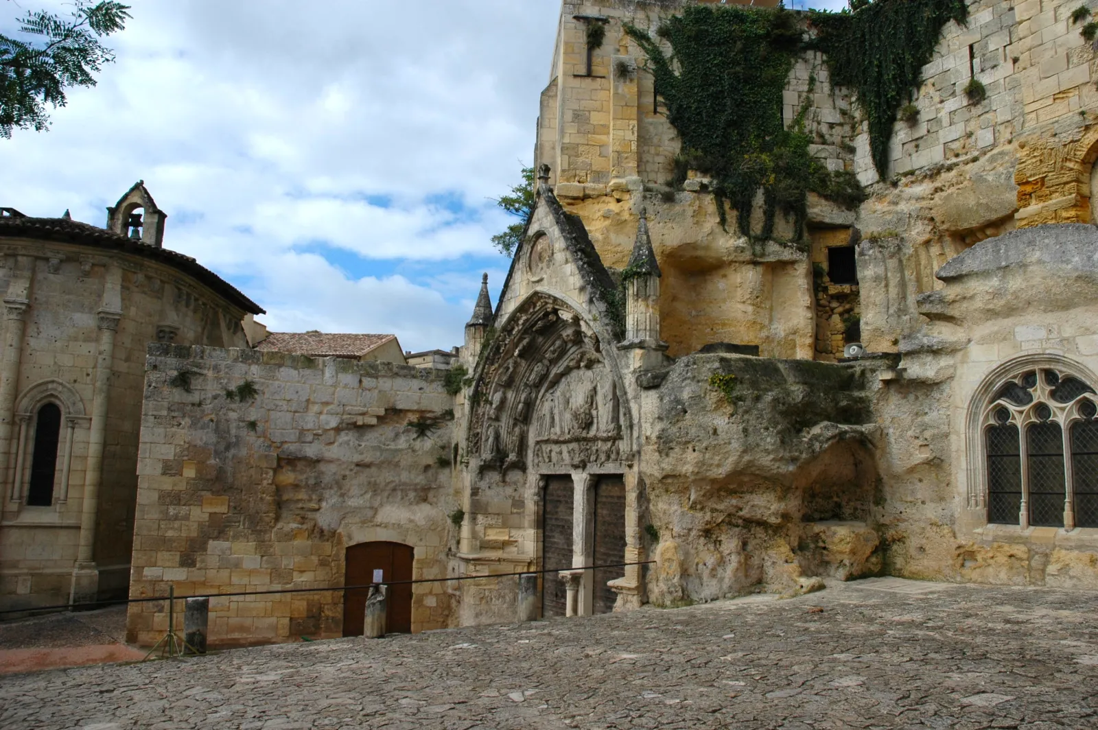 Ruins of a medieval stone church with Gothic portal, stained glass windows and ivy in the underground village of Saint-Émilion