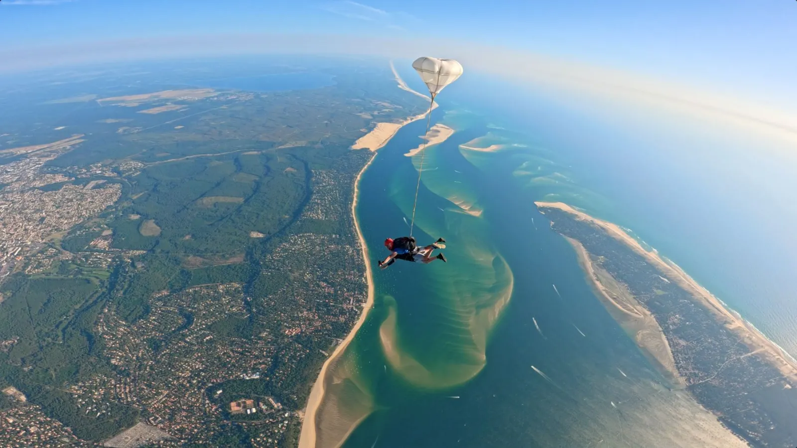 Skydiver in freefall above the Gironde estuary near Bordeaux, with aerial view of sandy beaches, forests and urban areas