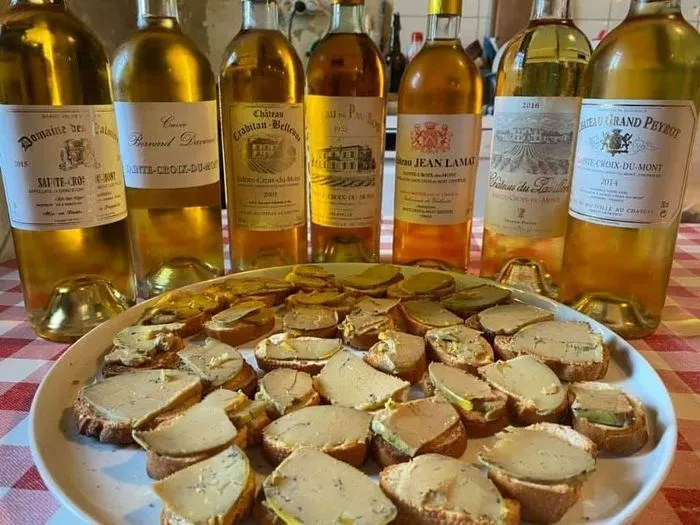 A plate of foie gras on toast surrounded by seven bottles of white and rosé wines from Bordeaux, during a tasting at the open doors of Sainte-Croix-du-Mont château.