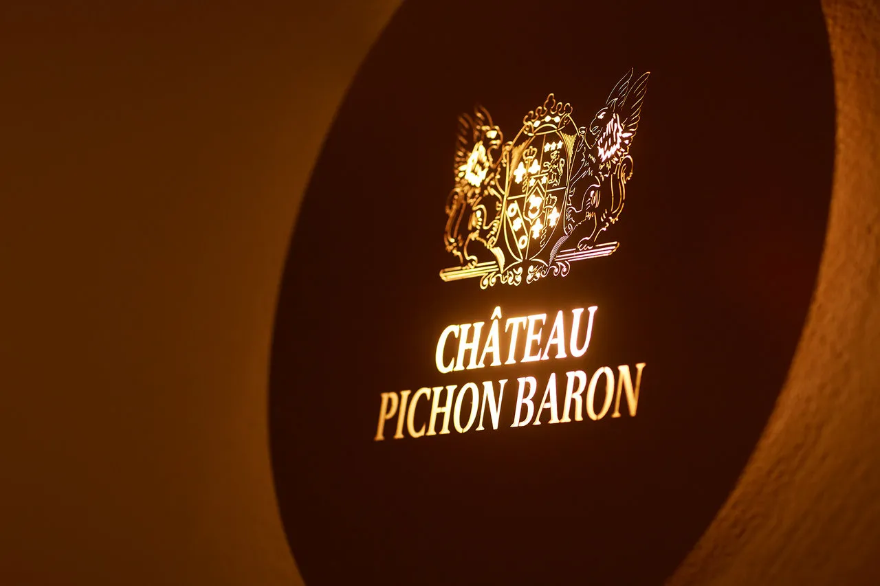 Wine label of Château Pichon Baron from Bordeaux with golden coat of arms on burgundy background