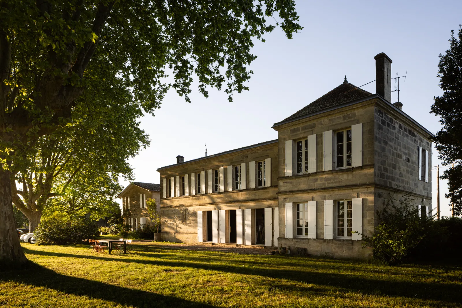 Les Joualles Cormeil Figeac Castle near Bordeaux, a stately stone mansion with white shutters surrounded by manicured gardens and ancient trees