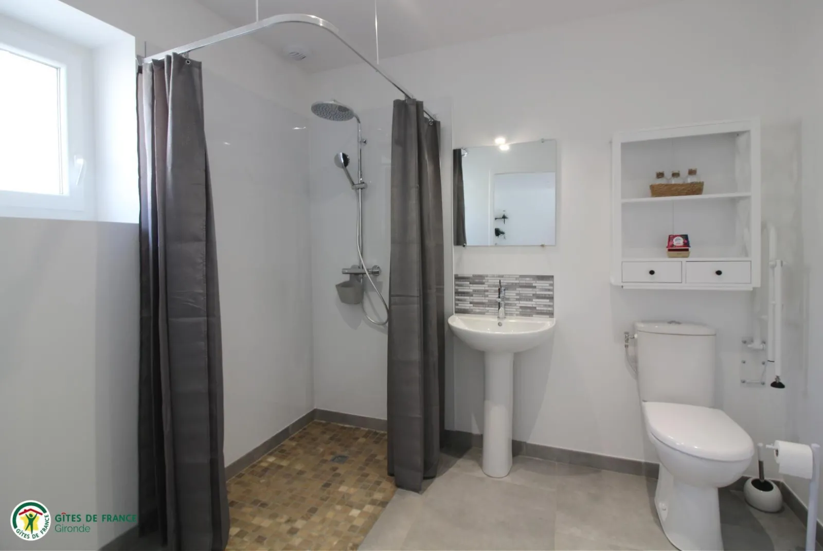 Modern bathroom featuring a walk-in shower, pedestal sink, toilet, mirror and white wall storage at the Tanins cottage, Château Pierre de Montignac in Bordeaux