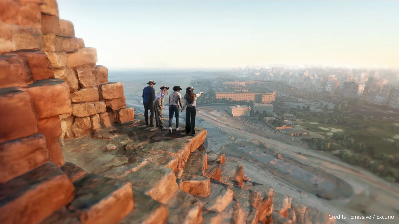 Four people standing on a rocky outcrop overlooking the city of Bordeaux, with panoramic views of the estuary, historic buildings, and urban landscape against a clear sky.