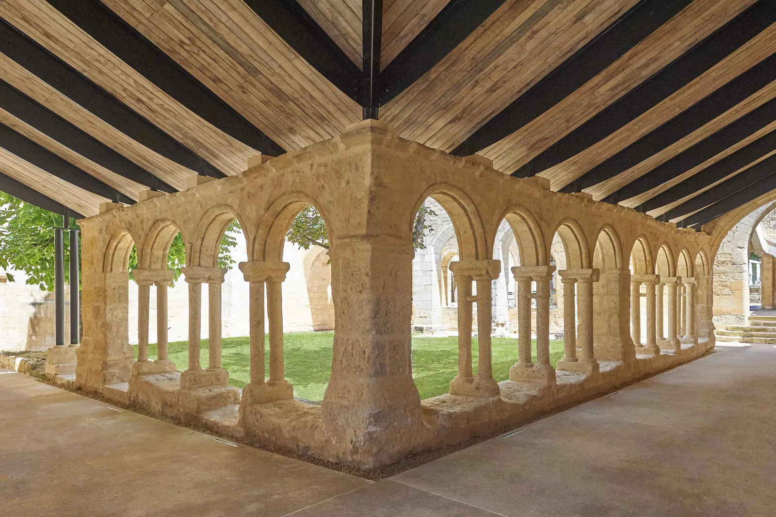 Cloister gallery of the Cordeliers in Bordeaux featuring Romanesque stone arcades with columns and exposed wooden beam ceiling