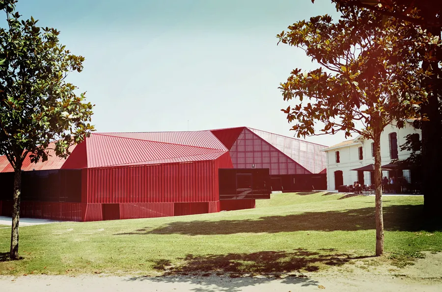 Rocher de Palmer in Cenon featuring modern red metal-roofed buildings and a historic white stone building set in a green landscaped park.