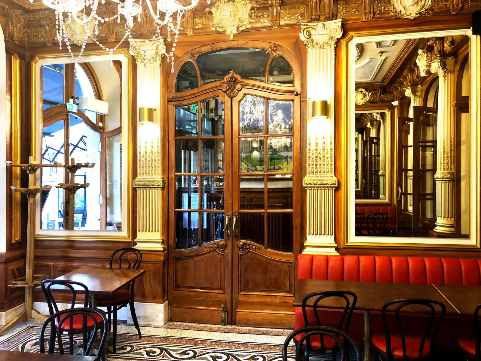 Elegant interior of QuatrèS Café in Bordeaux featuring gilt woodwork, Belle Époque furniture, framed mirrors and red velvet seating