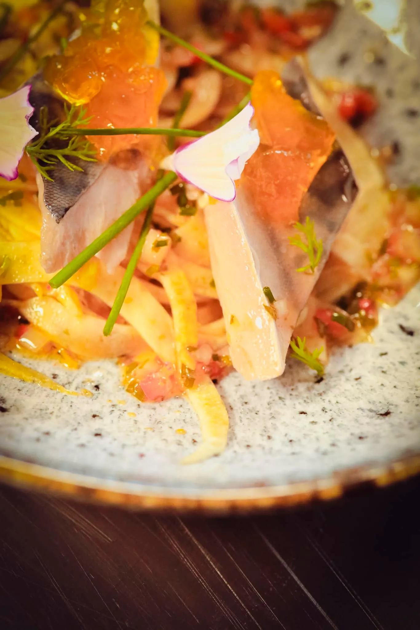 Gourmet dish plated on gray dish with colorful garnishes, fresh herbs and delicate finishing touches, served at Magnus restaurant in Bordeaux
