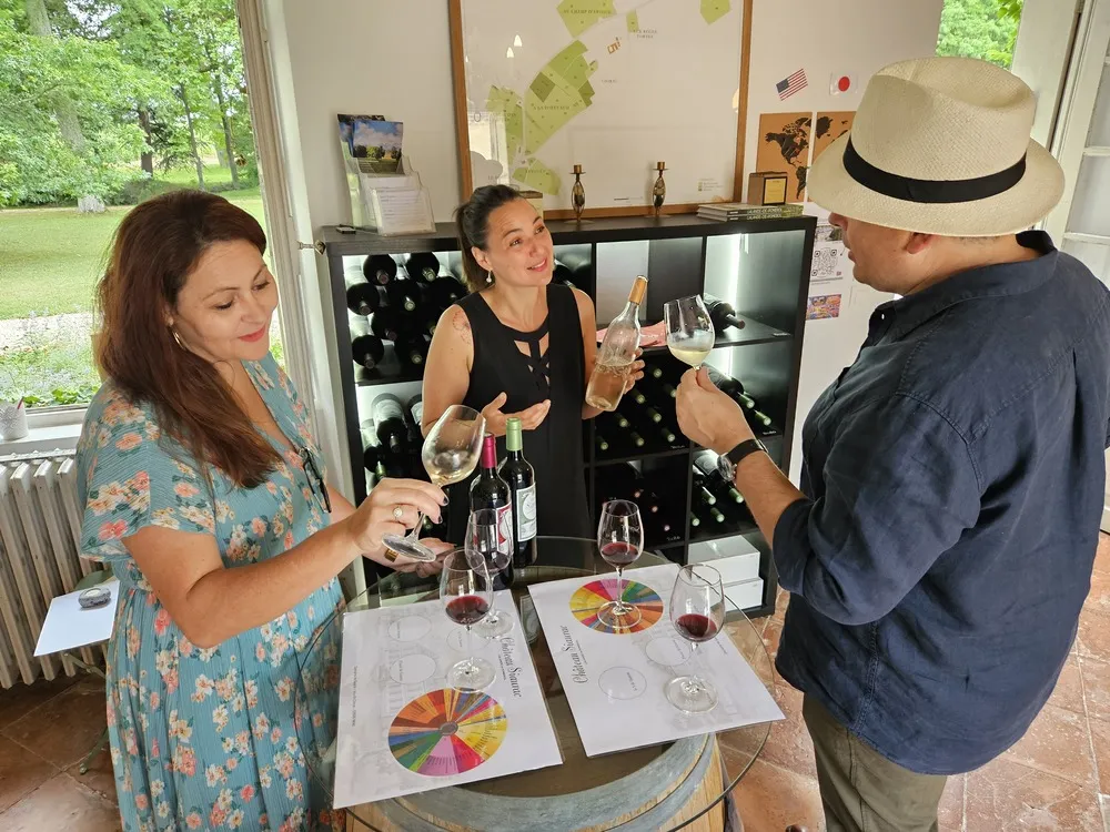Three people wine tasting at Château Siaurac in Bordeaux, with glasses, bottles, and tasting color wheels on a table.