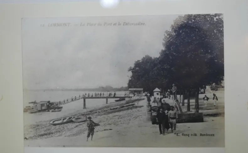 Vintage postcard depicting the port and Dordogne river at Lormont, featuring pedestrians on the beach, moored boats, and trees in the background.