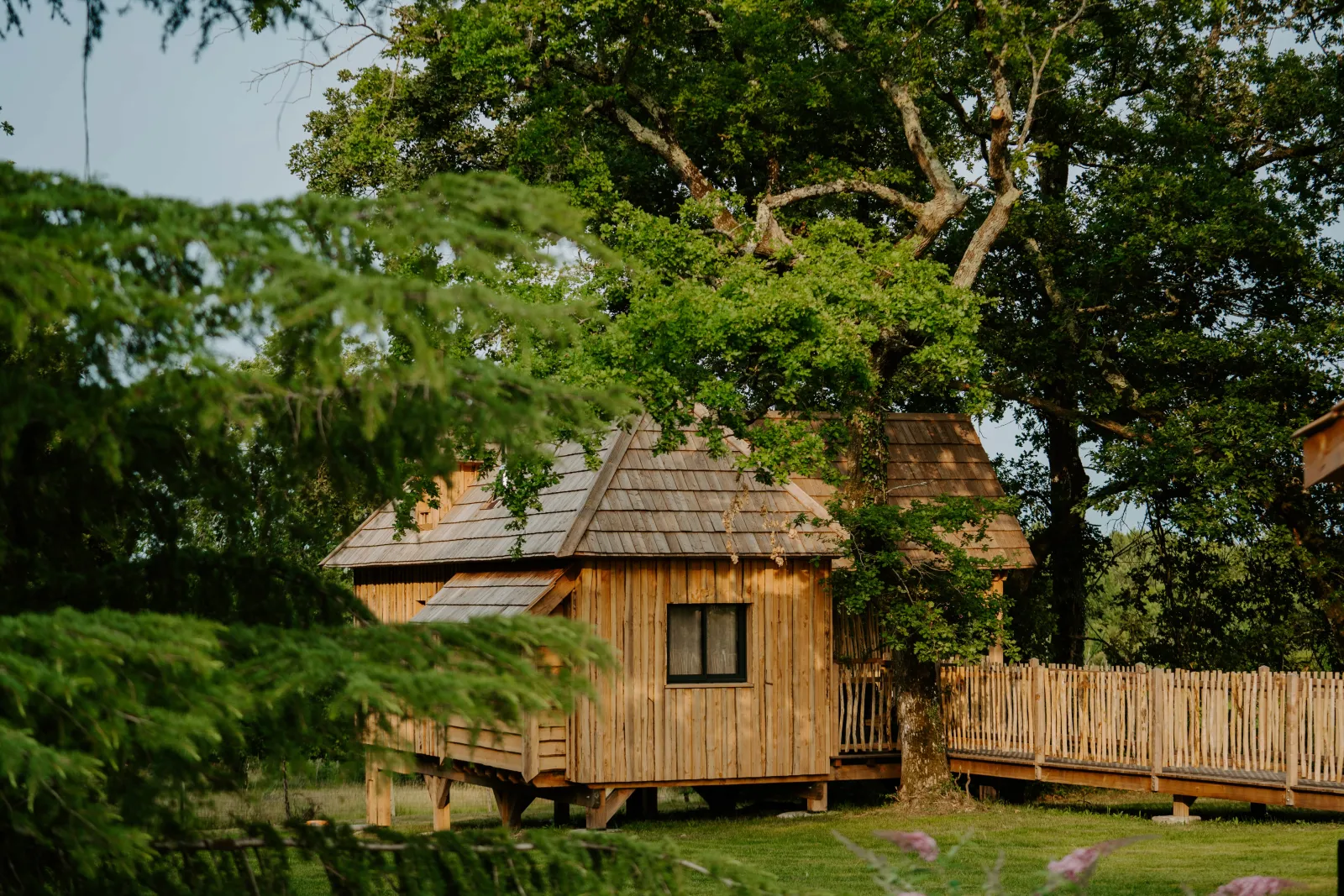 Traditional wooden Girondine cabin with pointed roof, surrounded by trees and greenery, characteristic of Bordeaux vernacular architecture.