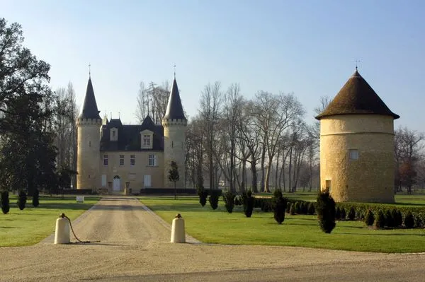 Château d'Agassac in Bordeaux, medieval fortress with pointed towers, tree-lined driveway and cypress roundabout in a green park