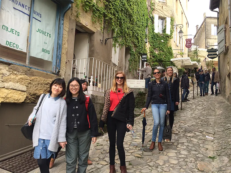 Tourists walking through a cobblestone street in old Bordeaux, surrounded by historic architecture and ivy-covered buildings