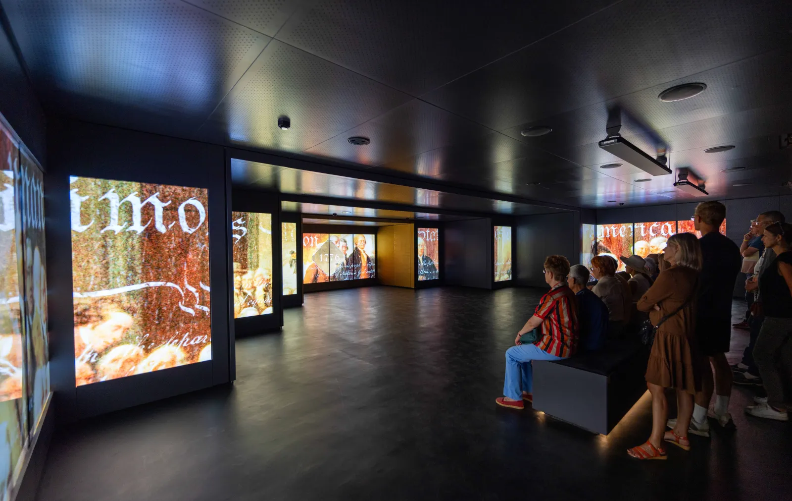 Visitors in an interactive exhibition at the Hennessy house in Bordeaux, surrounded by illuminated digital screens showcasing the cognac brand's heritage.