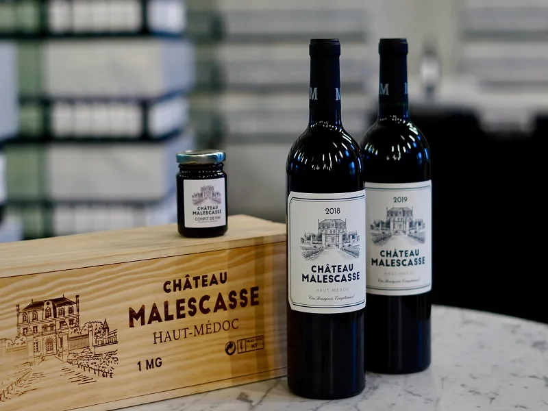Château Malescasse Bordeaux wine collection featuring a wooden gift box 1 MG, a 2018 vintage bottle, a 2019 vintage bottle of Haut-Médoc wine, and a jar of château preserve.