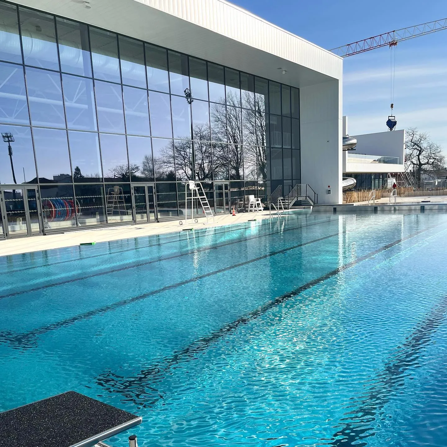 Interior view of the Olympic swimming pool at UCPA Aqua Stadium in Mérignac, Bordeaux, featuring well-marked lanes and a modern glass facade