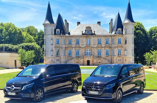 Two black Mercedes sedans parked in front of a Bordeaux-style château with towers and turrets, surrounded by greenery.