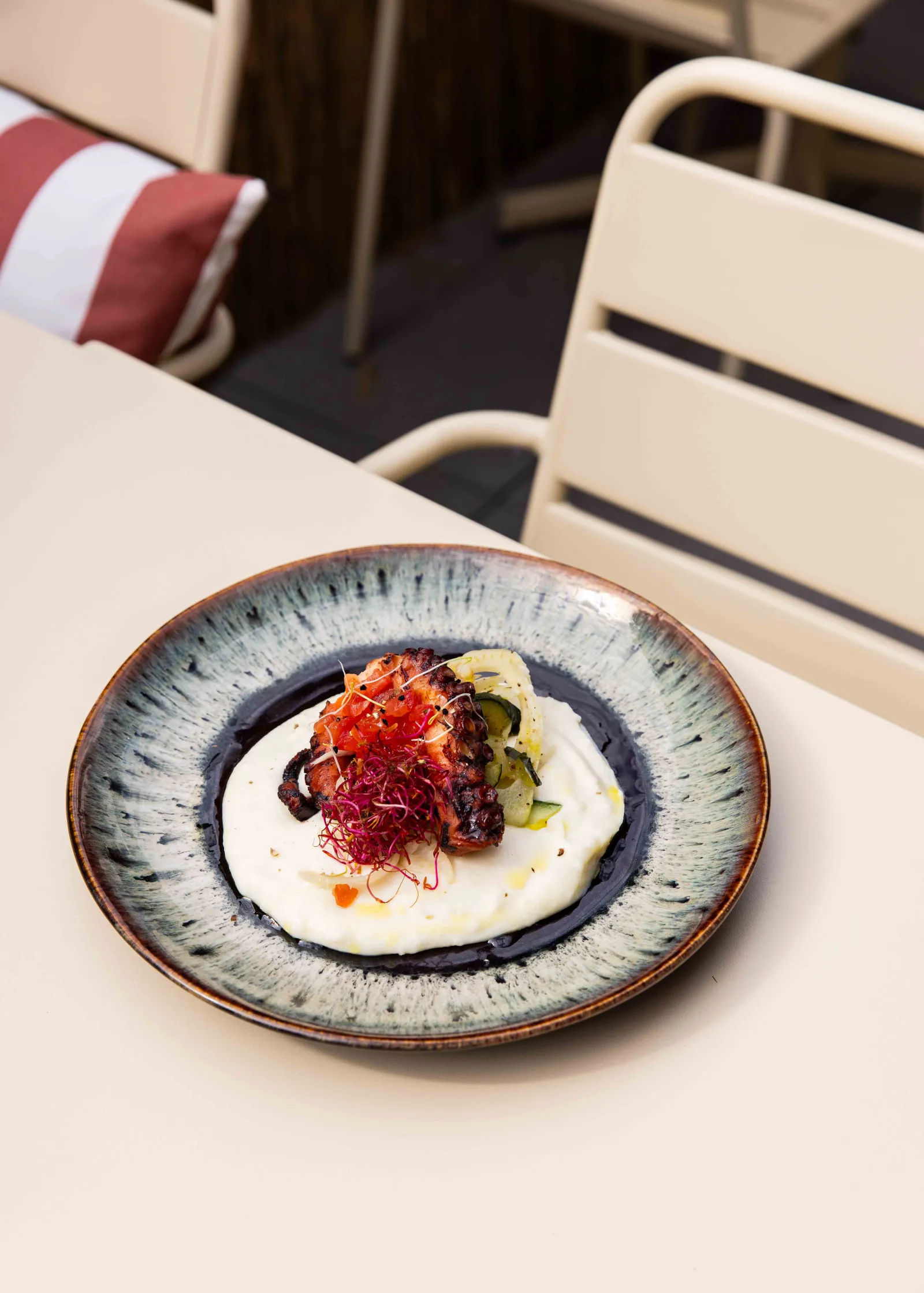 Fine dining plate from Le Lago restaurant in Bordeaux, featuring a white mousse topped with thinly sliced red beets and microgreens, presented on a blue and white ceramic plate.