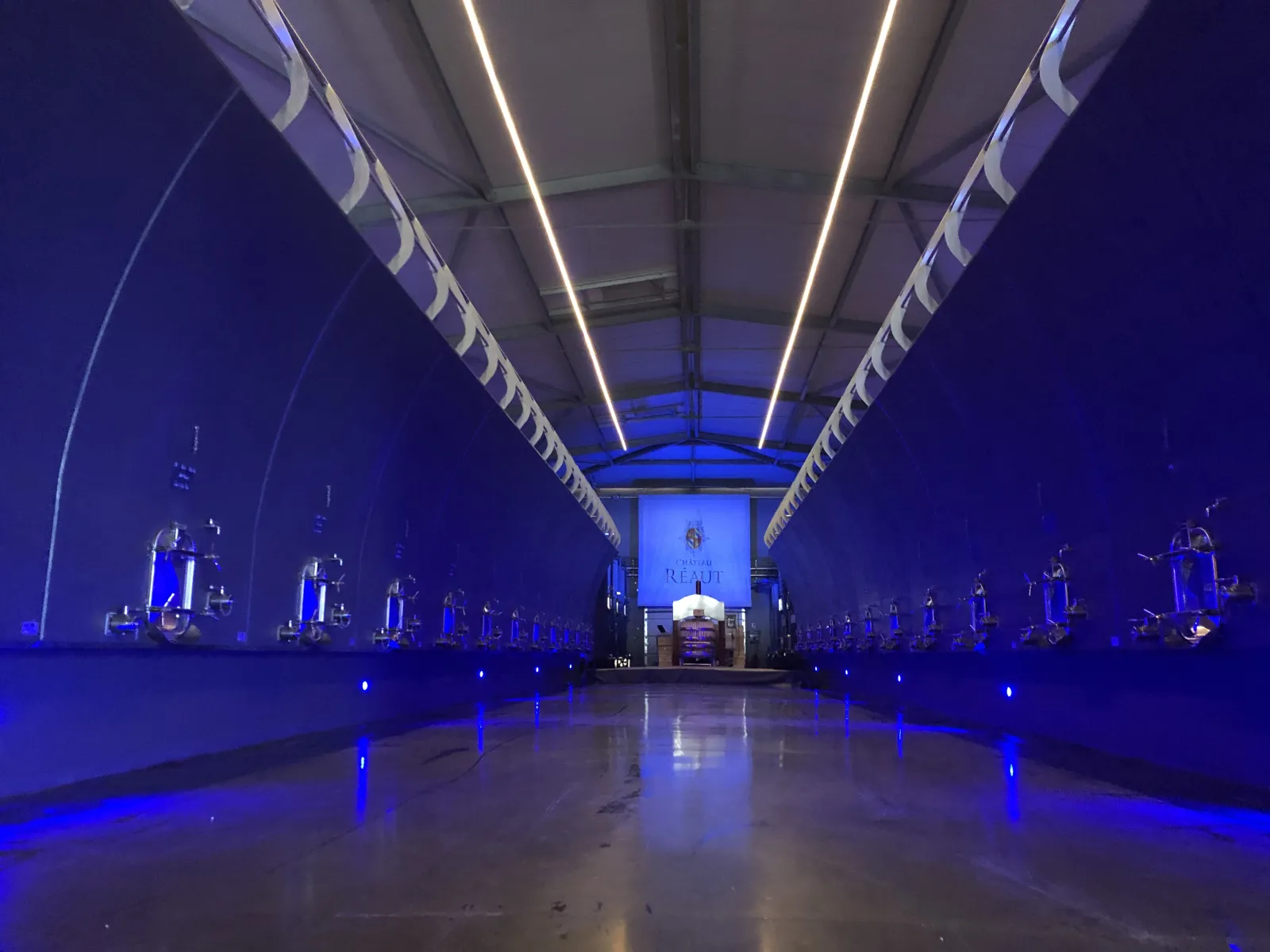Futuristic interior of Château Réaut in Bordeaux featuring arched architecture, blue neon lighting, and reflective flooring