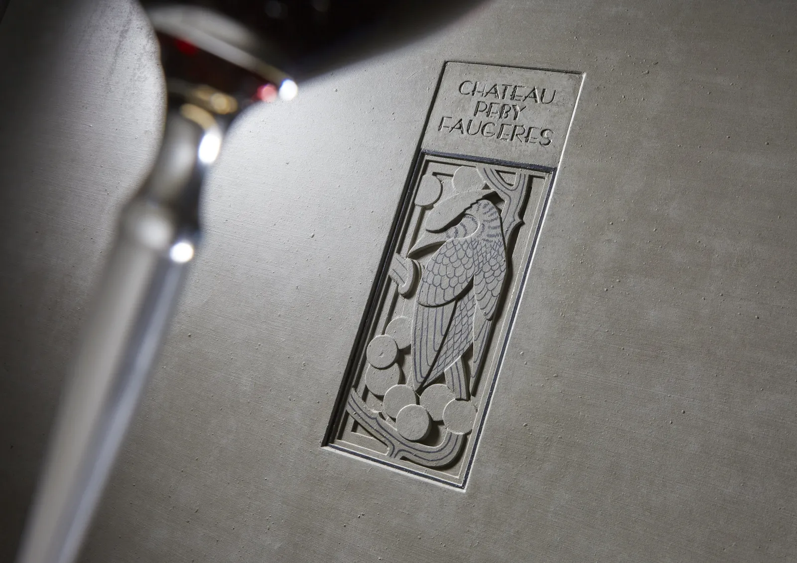 Close-up of an engraved plaque from Château Peby Faugères in Bordeaux, featuring a relief design of grapes and vine leaves.
