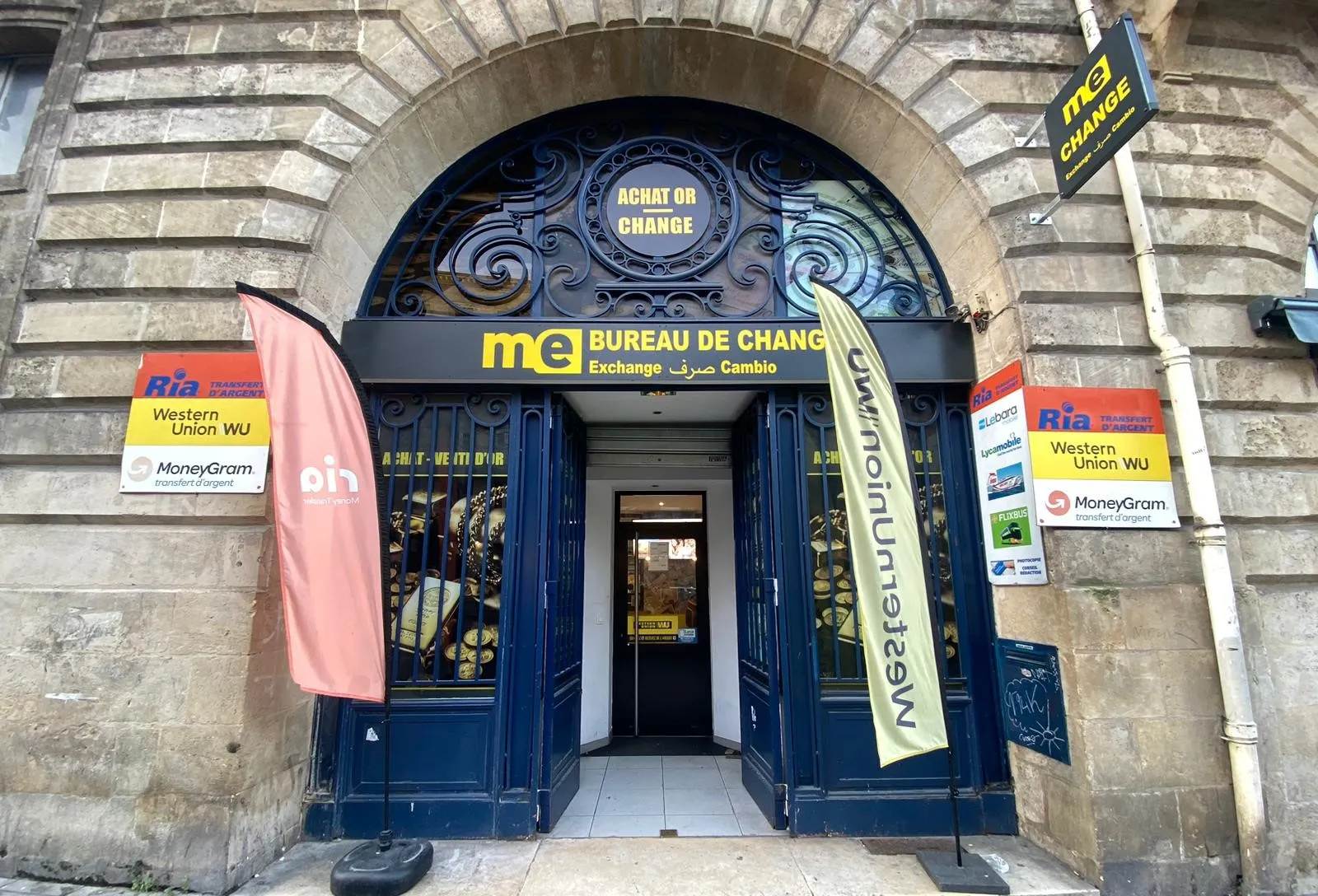 Monex Exchange currency exchange office in Bordeaux, featuring ornate blue doors, stone archway, Western Union and MoneyGram signs, located at Gambetta.