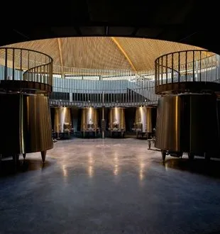 Interior of the Bordeaux Dome featuring polished concrete floor, metal railings on balconies, cylindrical columns, and a curved wooden perforated ceiling.