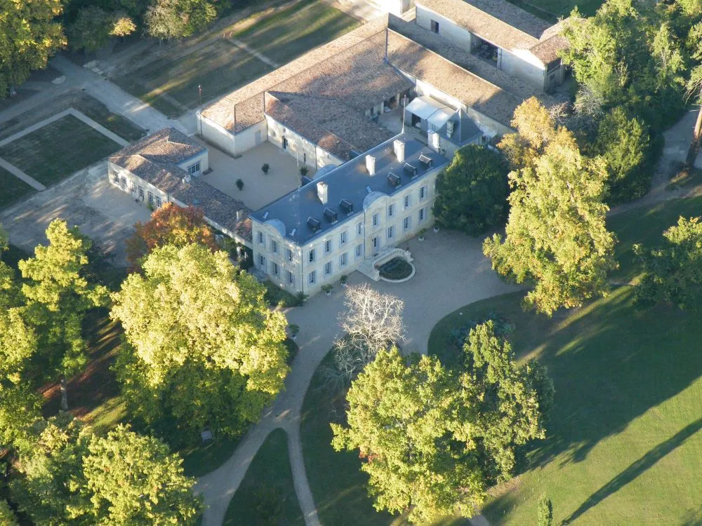 Aerial view of Château Siaurac in Bordeaux, a classical white stone building with slate roof, surrounded by manicured gardens and mature trees