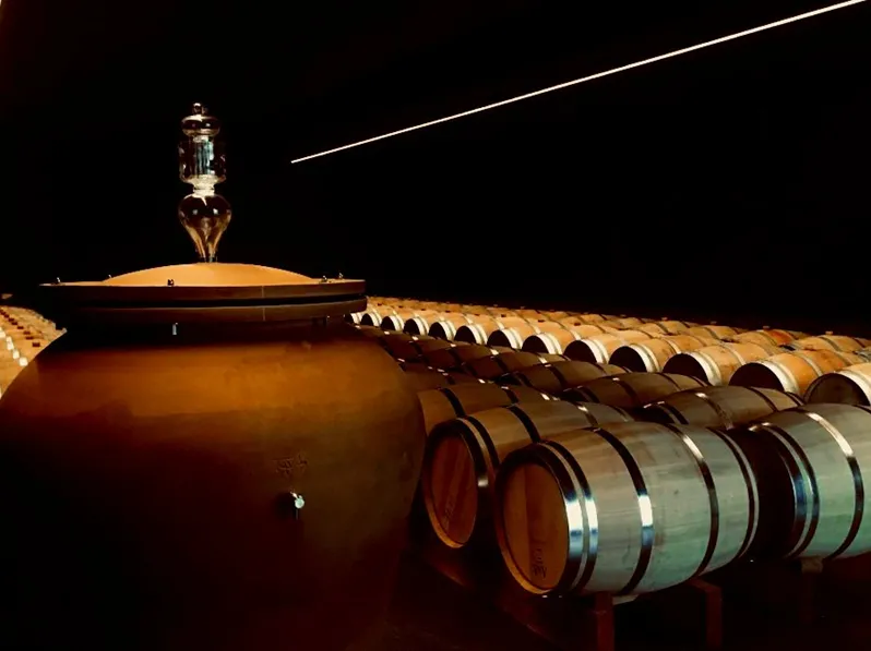 Rows of illuminated wine barrels at night in Château Réaut cellar in Bordeaux, with overhead lighting