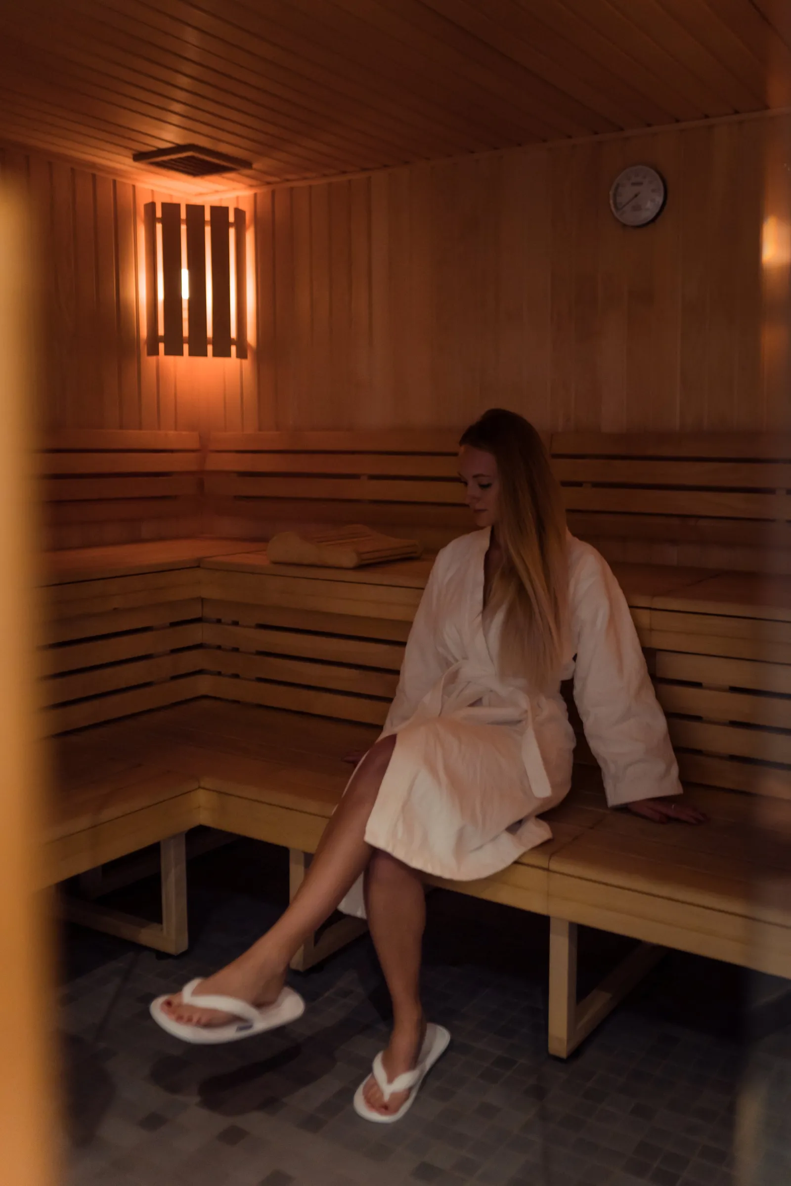 Woman in white bathrobe relaxing in a wooden sauna at Radisson Blu Hotel Bordeaux