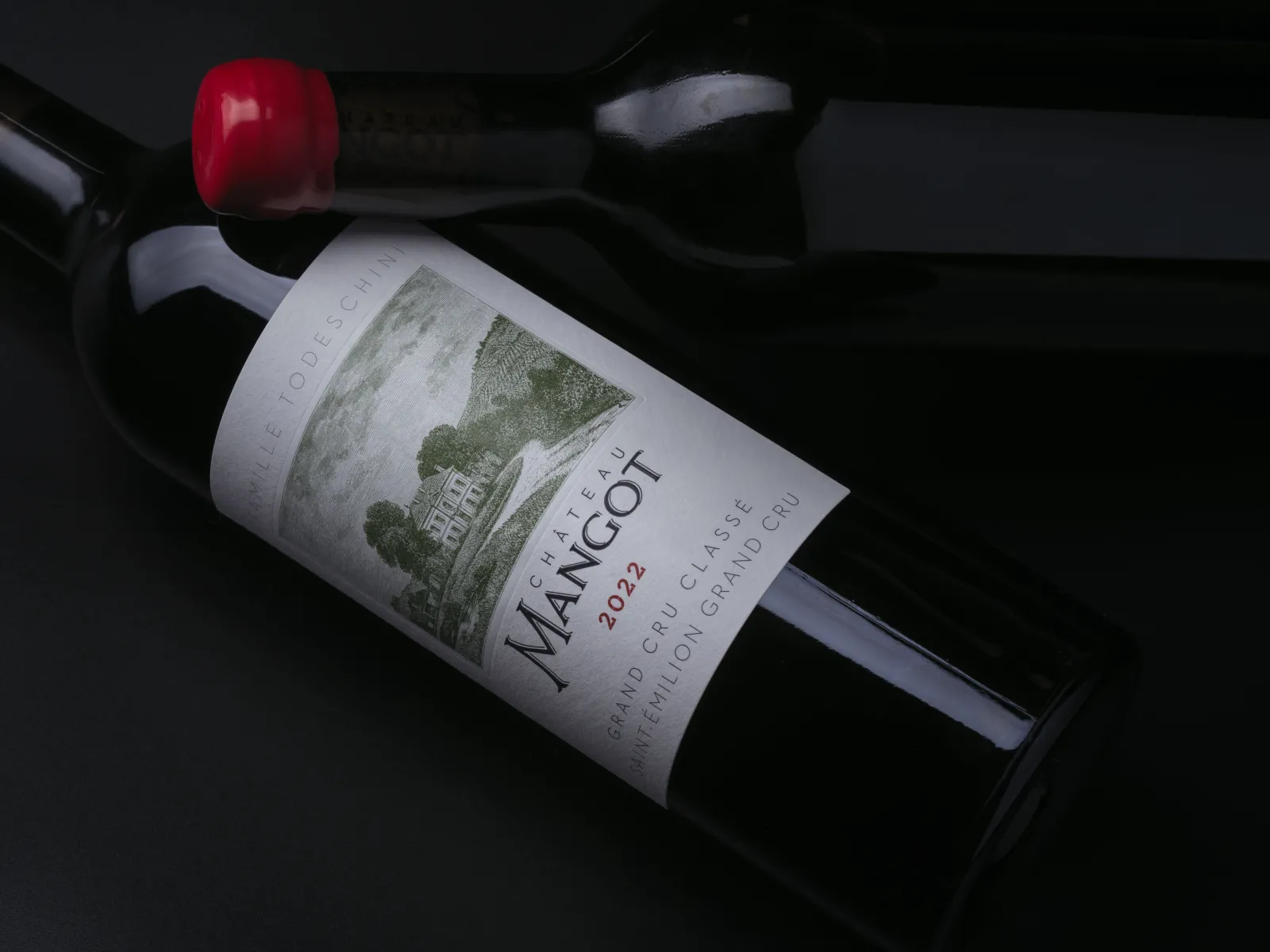 Bottle of Château Mangot 2022 red wine, Bordeaux grand cru, displayed on a black background with a red cork stopper