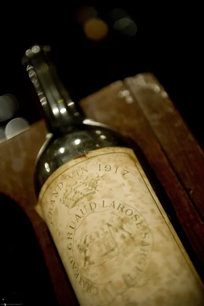 Bottle of Château Gruaud Larose Bordeaux wine with vintage label dated 1918, photographed at night against a blurred background.