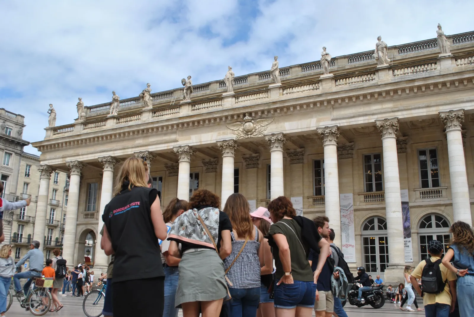 Tourists viewing the neoclassical facade of the Grand-Théâtre de Bordeaux with its Corinthian columns and statues on Place de la Comédie