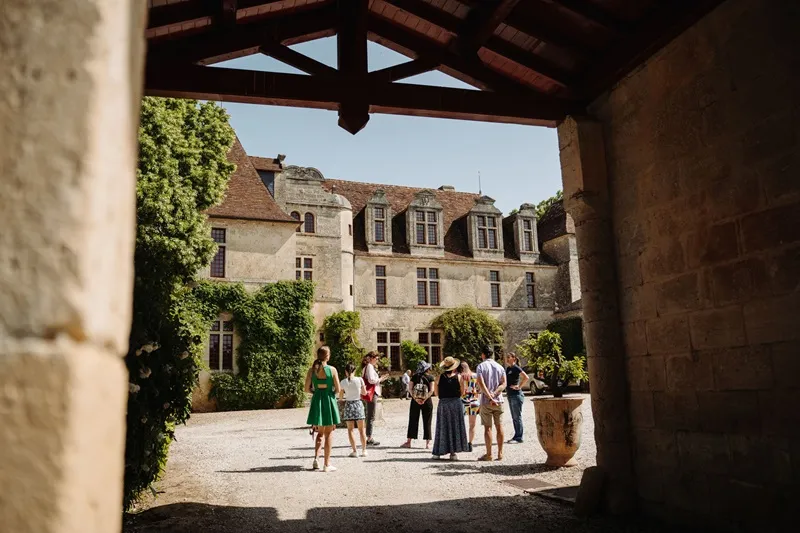 Inner courtyard of Château Le Grand Verdus in Bordeaux featuring a stone mansion facade with visitors in the sunny plaza