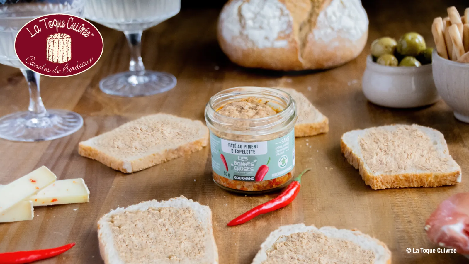 Gourmet tasting platter featuring espelette pâté, toasted bread, cheese, olives, crackers and white wine glass, presented by La Toque Cuivrée in Bordeaux