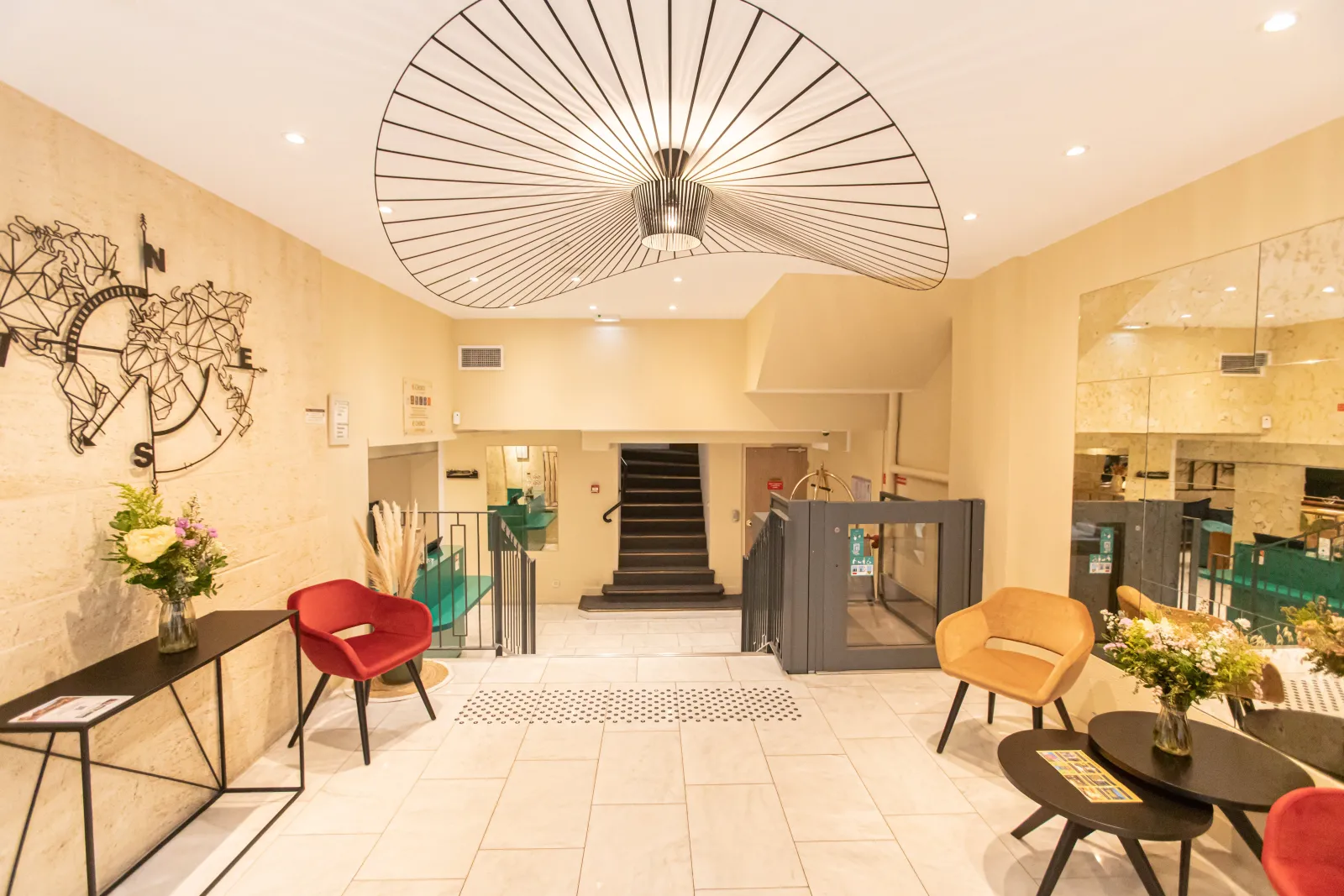 Modern lobby of Quality Hôtel Bordeaux Centre featuring a designer ceiling, contemporary colored furniture, staircase in the background, and minimalist décor