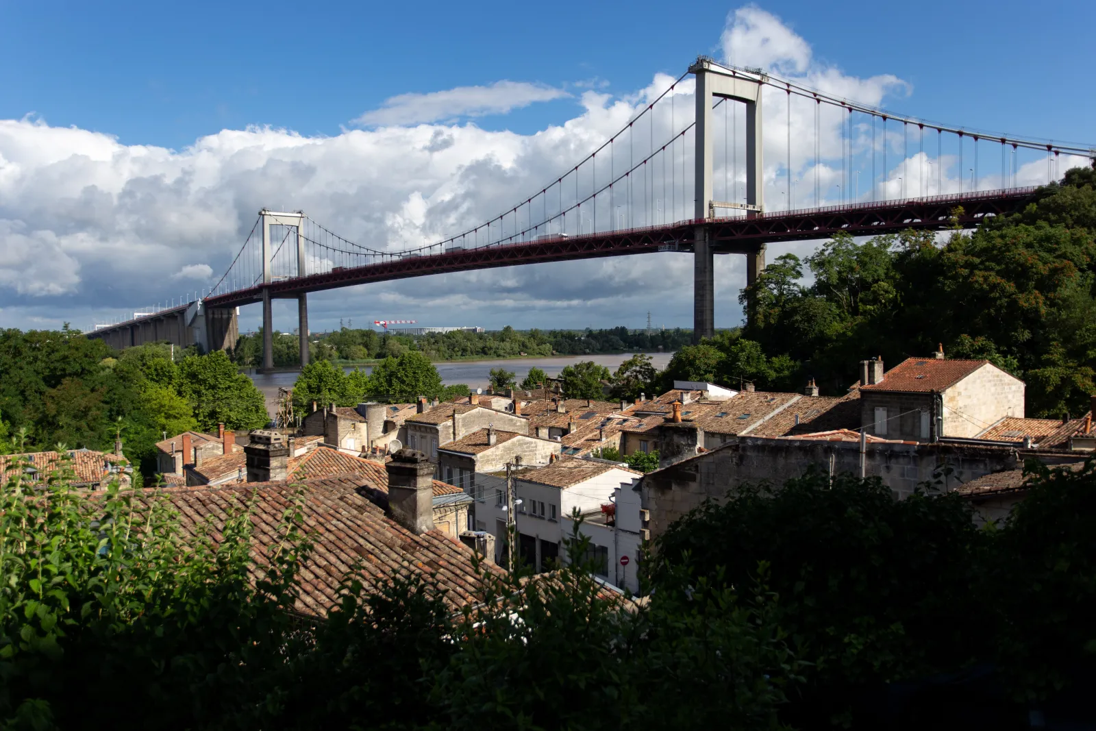 View of the Aquitaine Bridge spanning the Garonne River with the old Lormont district and its red-tiled roofs in the foreground, in Bordeaux.
