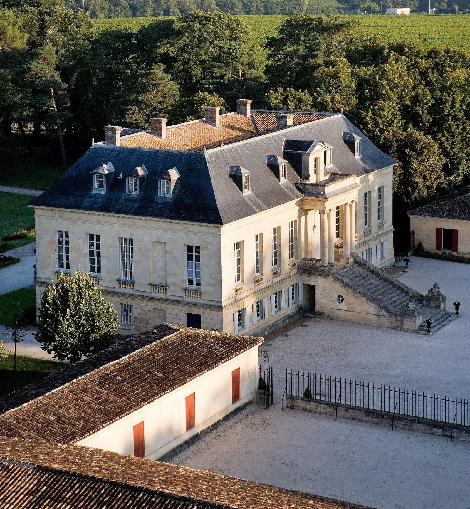 Aerial view of Château La Louvière in Bordeaux, an elegant 18th-century mansion with mansard roof, surrounded by vineyards and forests.