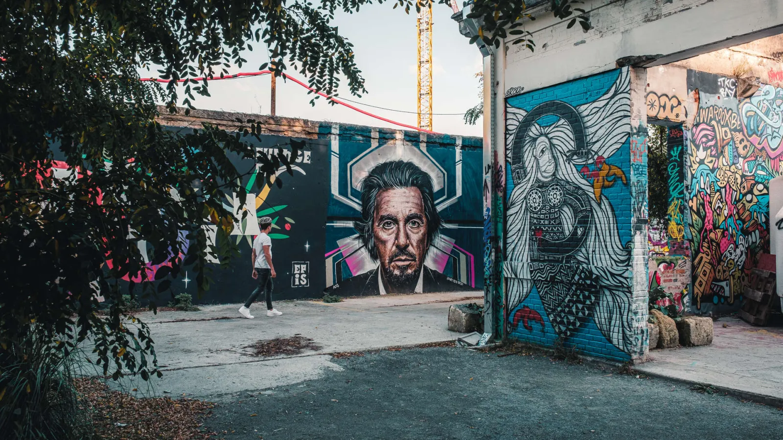 Street art gallery in Bordeaux Darwin featuring colorful murals with portrait artwork and abstract patterns on blue walls in an urban area.