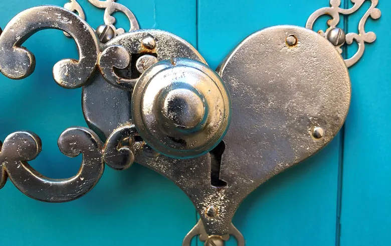 Ornamental bronze lock on a turquoise door of the Labottière mansion in Bordeaux, featuring a heart-shaped handle and rocaille motifs