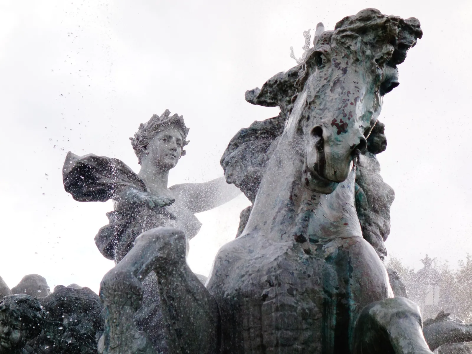 Stone statue featuring a winged figure riding an ornately decorated horse, covered in snow, in Hunting Town park in Bordeaux.