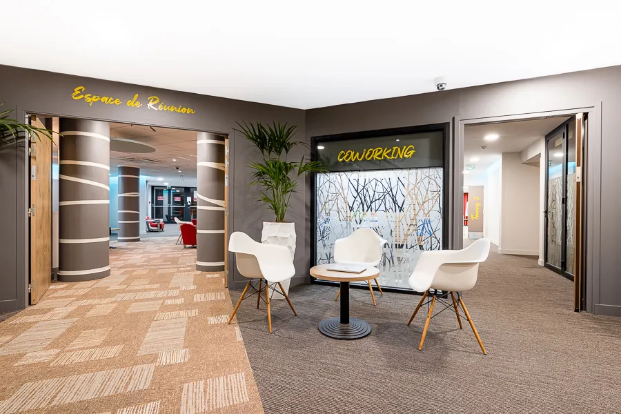 Modern coworking space at Ibis Bordeaux Centre Mériadeck featuring white armchairs, green plants, yellow signage and access to hotel facilities