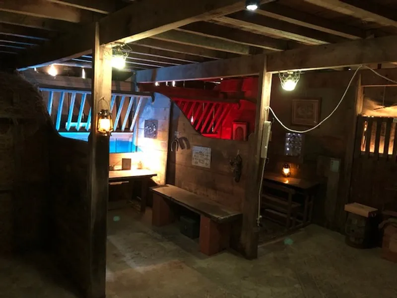 Escape room at Château de Lisennes in Bordeaux, featuring blue and red neon lights, wooden benches, ambient lighting and immersive decorative elements