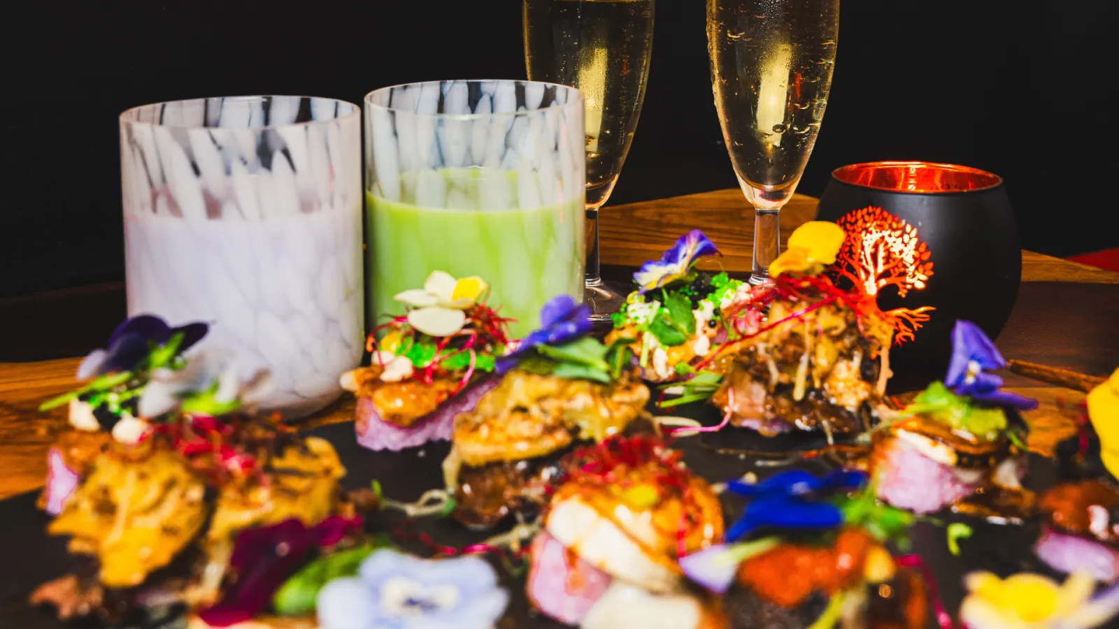Elegant table display with gourmet canapés decorated with colorful edible flowers, champagne and cocktail glasses in Bordeaux