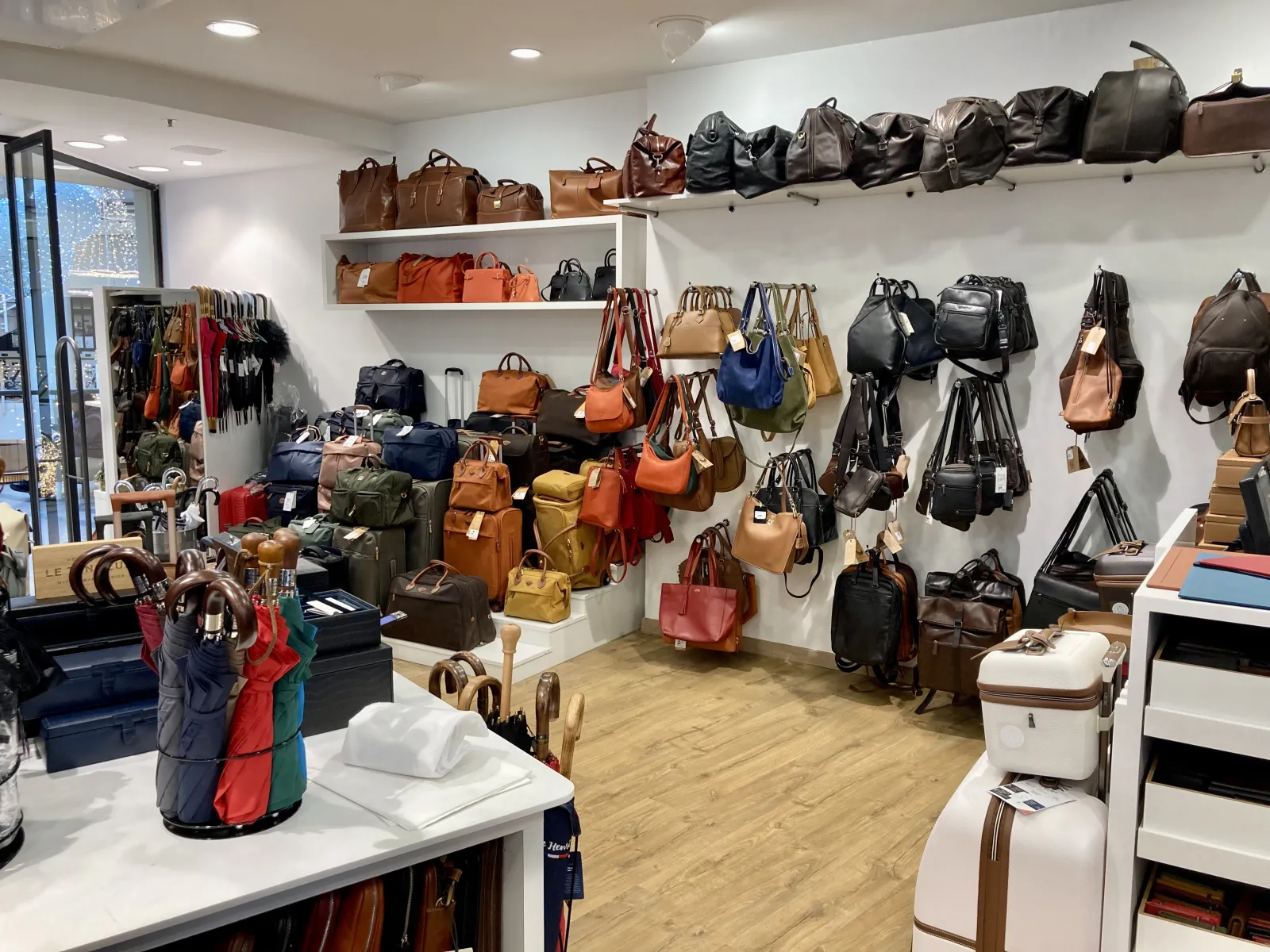 Interior view of Massip Maroquinerie shop in Bordeaux displaying a wide selection of leather handbags, luggage, and accessories arranged on wall shelves and floor displays.