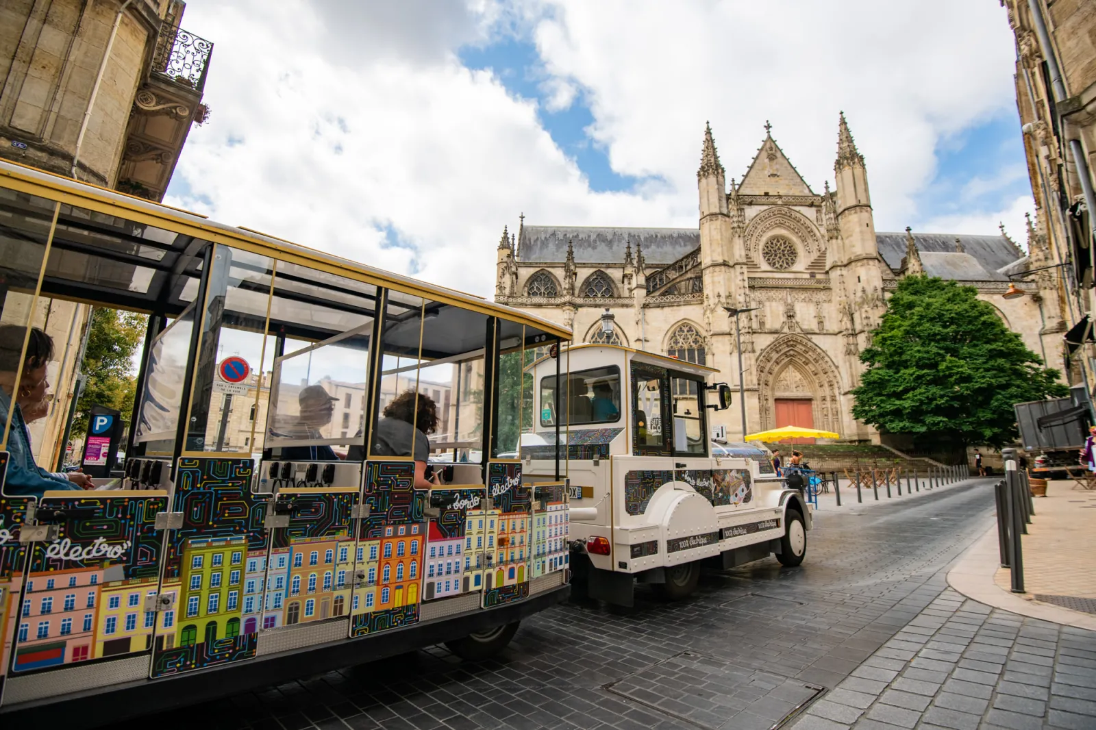 Bordeaux's electric tourist train in front of Saint-André Cathedral, with cars decorated with colorful city building facades