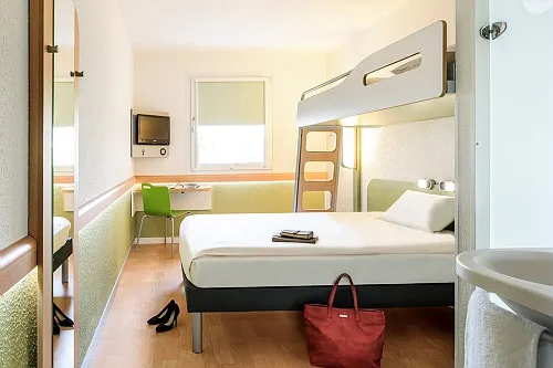 Compact hotel room with single bed, bunk bed, desk, green chair and ensuite bathroom at Bordeaux budget hotel