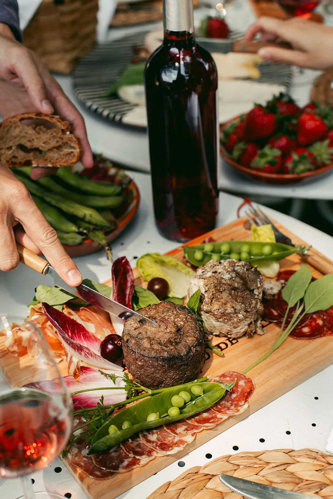Gourmet dining table featuring grilled meats, cured meats, fresh vegetables and red wine from Château de Cérons in Bordeaux