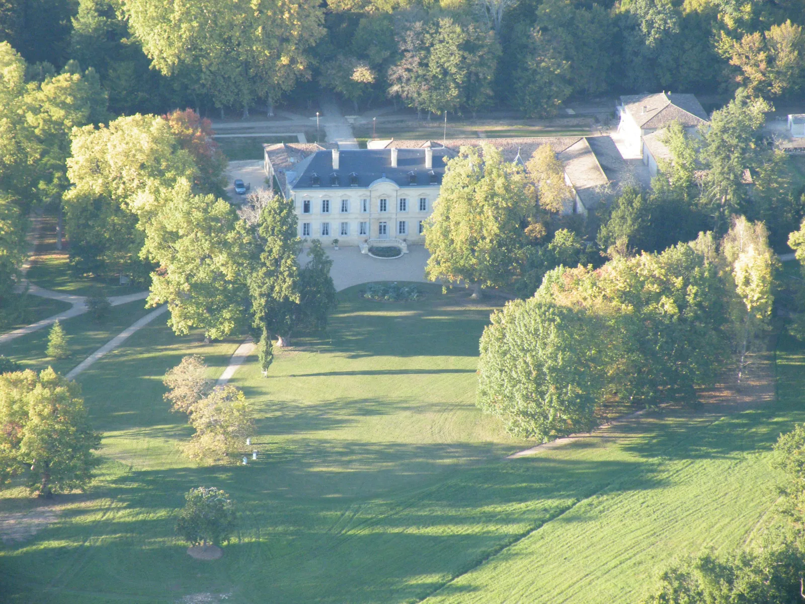 Aerial view of Siaurac estate near Bordeaux, a white classical mansion surrounded by mature trees and green lawns with water features