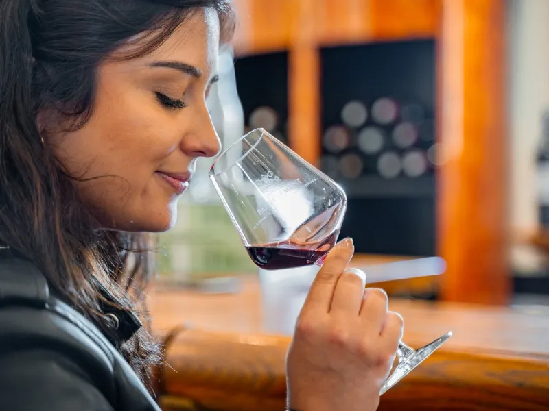Woman tasting a glass of red wine in Bordeaux, with an elegant interior in the background